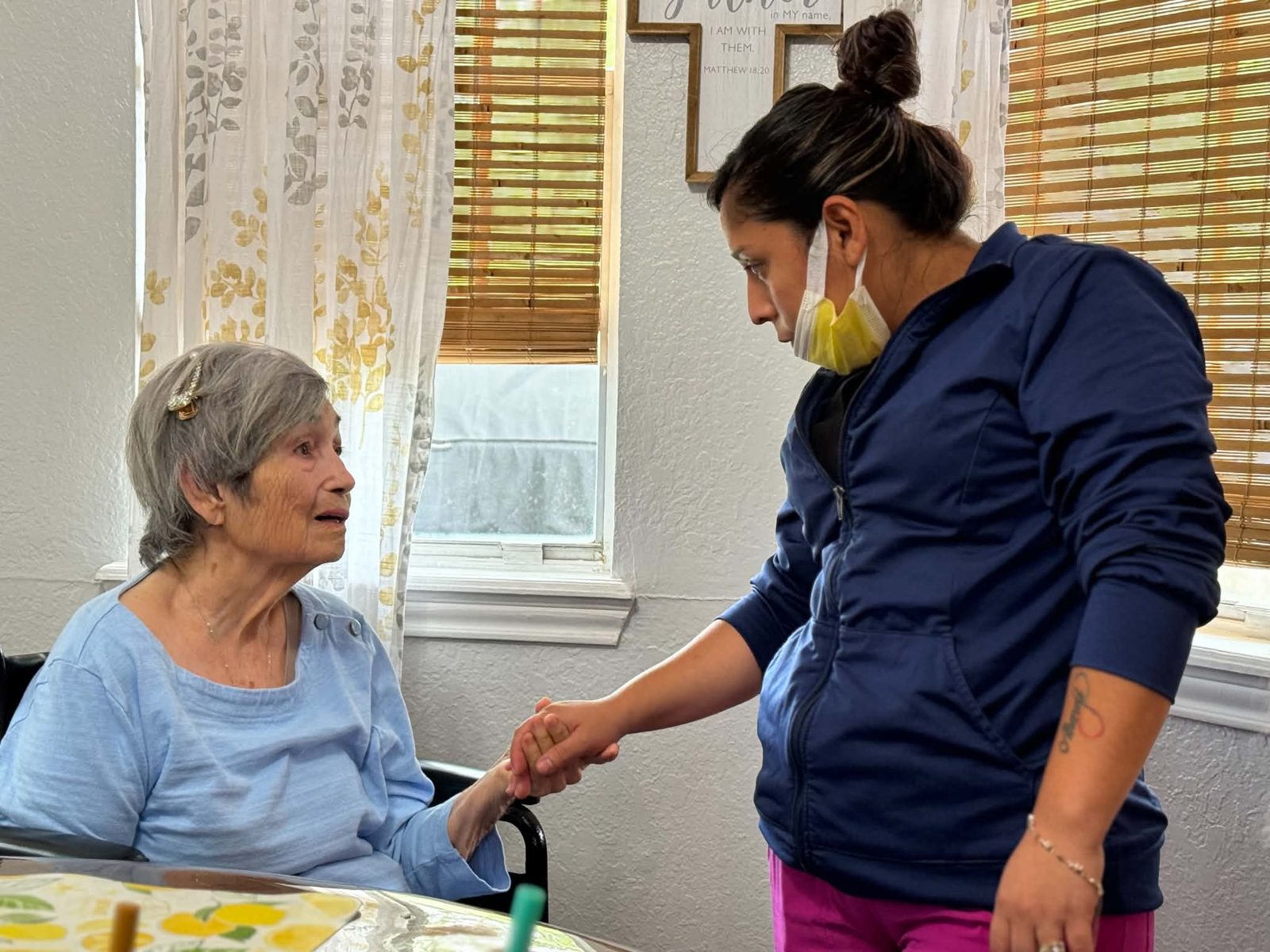 A caregiver gently holding hands with a resident at Nona's Place