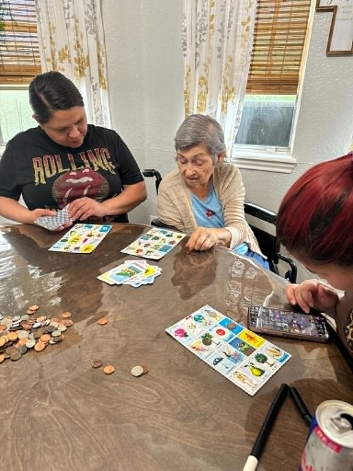 Family members playing lotería with a resident around the dining table